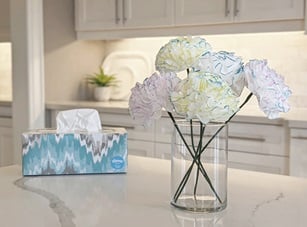 DIY paper flowers made out of Kleenex in a vase next to a box of Kleenex tissues